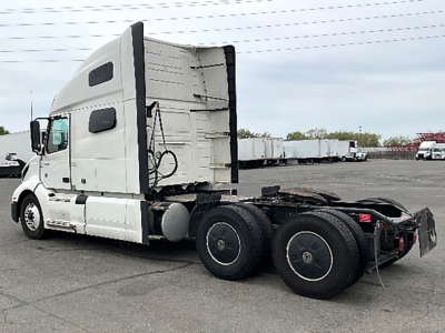 Volvo VNL 760 sleeper cab tractor truck side view showing rear dual-axle configuration and fifth wheel in a used truck lot.