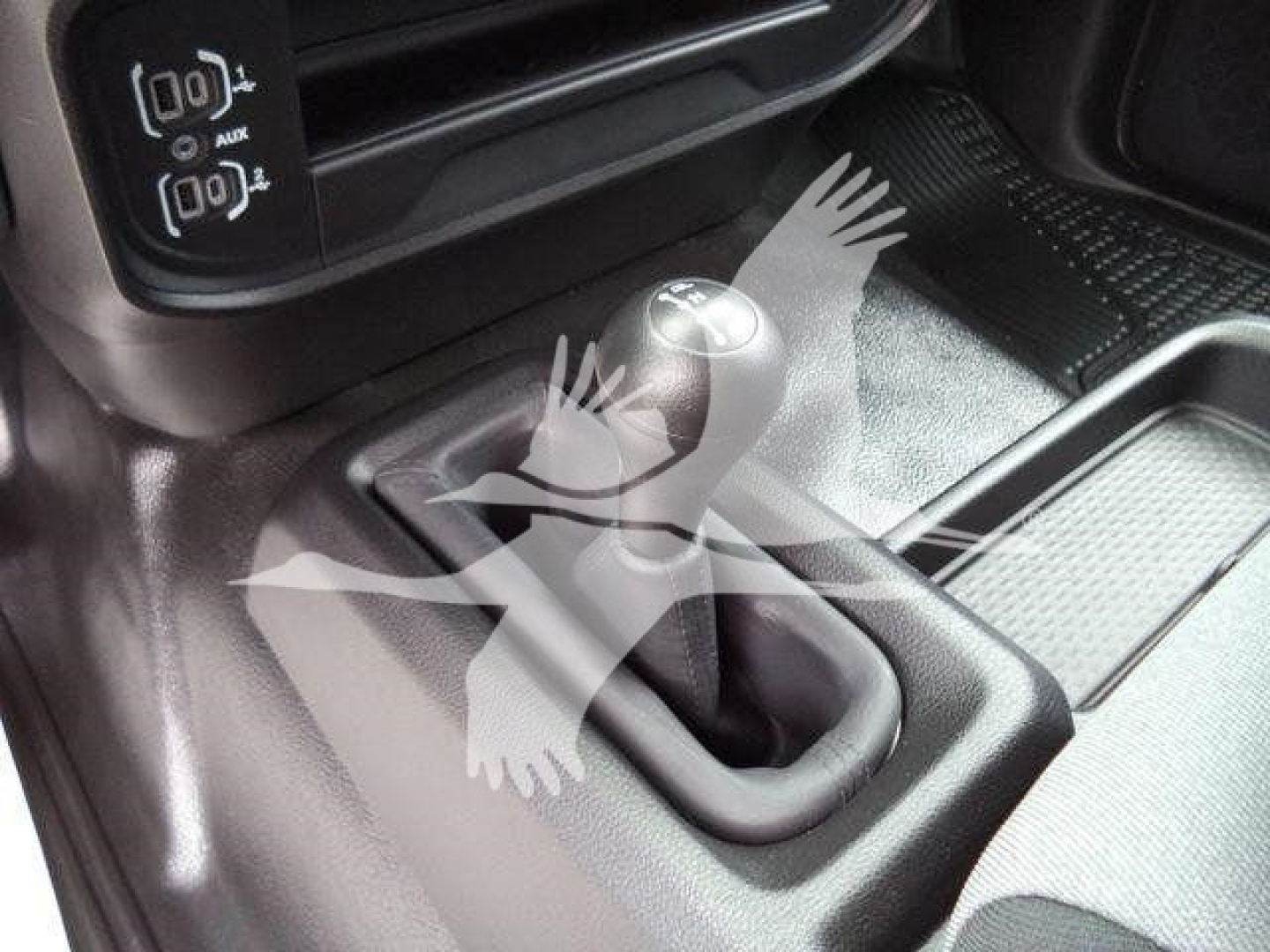 Ram 4500 cabin interior showing manual gear shift lever and center console with wiring icons on left; black textured surfaces and gear boot.