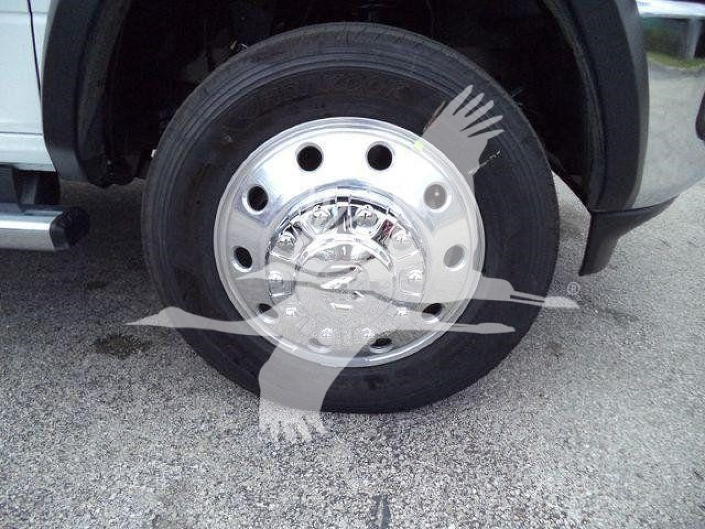 Front wheel and hubcap of a new Ram 4500 SLT truck showing chrome steel wheel and tire, wheel well fender, and part of suspension.