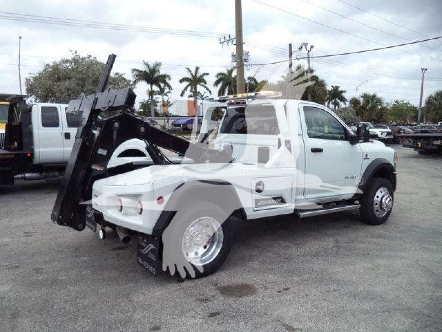 Ram 4500 tow truck side view showing winch gear and hydraulic lifting mechanism, white cab, dual rear wheels, dealership lot.