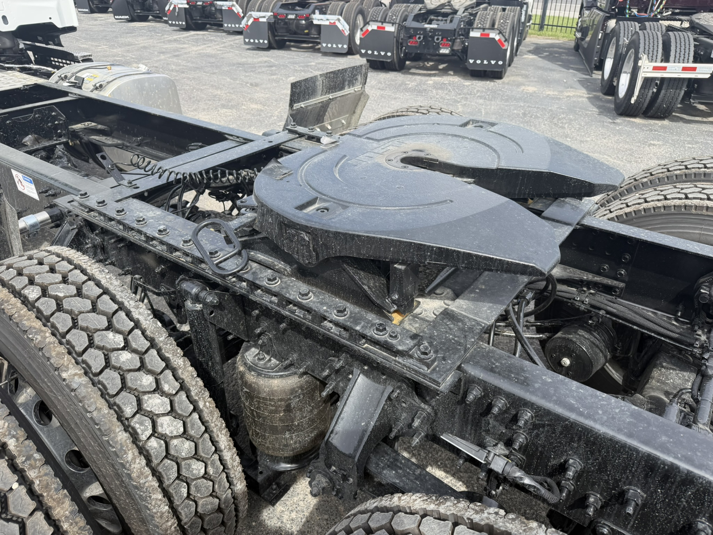 Chassis of a 2027 Mack AN64T conventional daycab showing the fifth-wheel housing and drivetrain area with dual rear axles and tire tread visible.