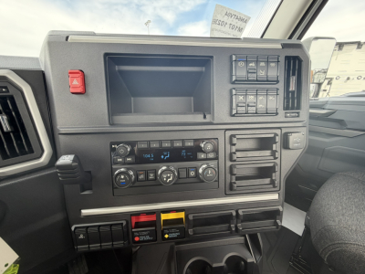 Dashboard view of a 2027 Mack AN64T truck showing center console with climate controls, radio, and multiple switches.