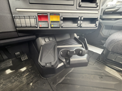 Cab interior showing control switches and dual cup holders in a 2027 Mack AN64T truck dashboard area.