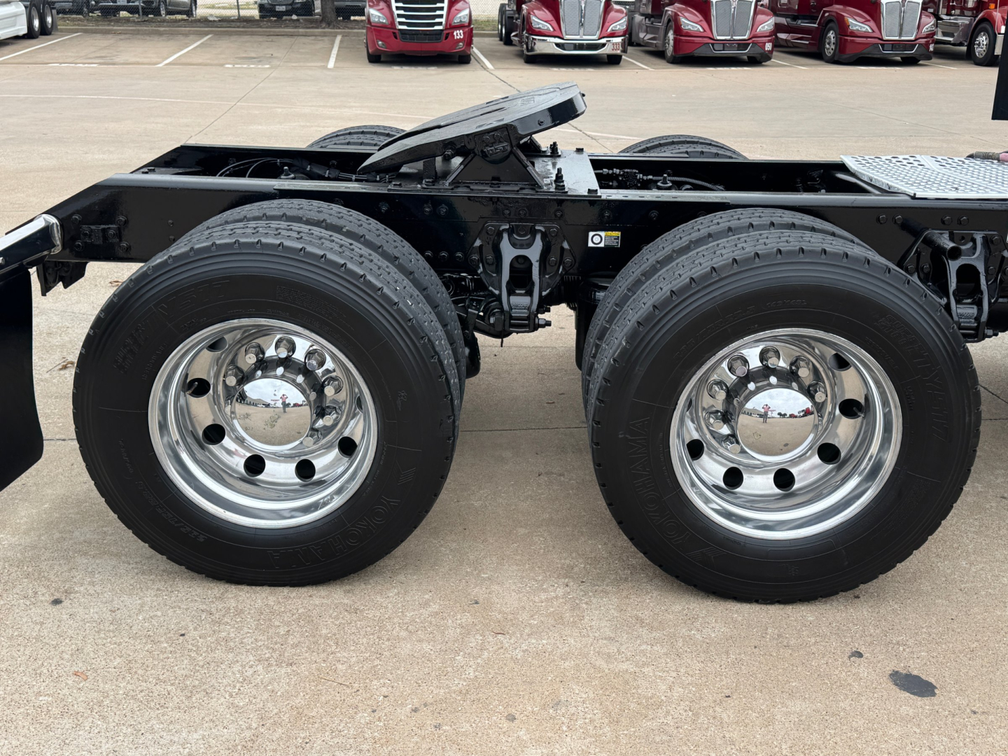 Kenworth T880 dual rear axles on frame with shiny chrome wheels and black chassis, side view of the undercarriage.
