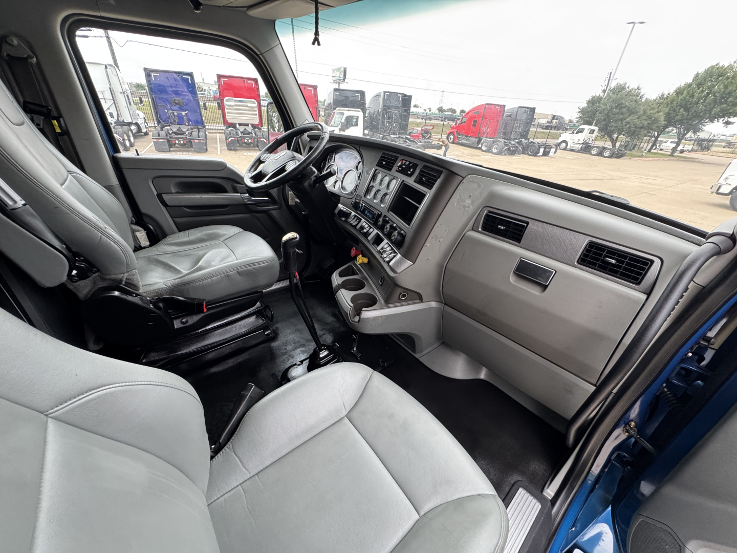 Interior of a 2019 Kenworth T880 cab, driver seat and dashboard visible with steering wheel, gauges, and center console.
