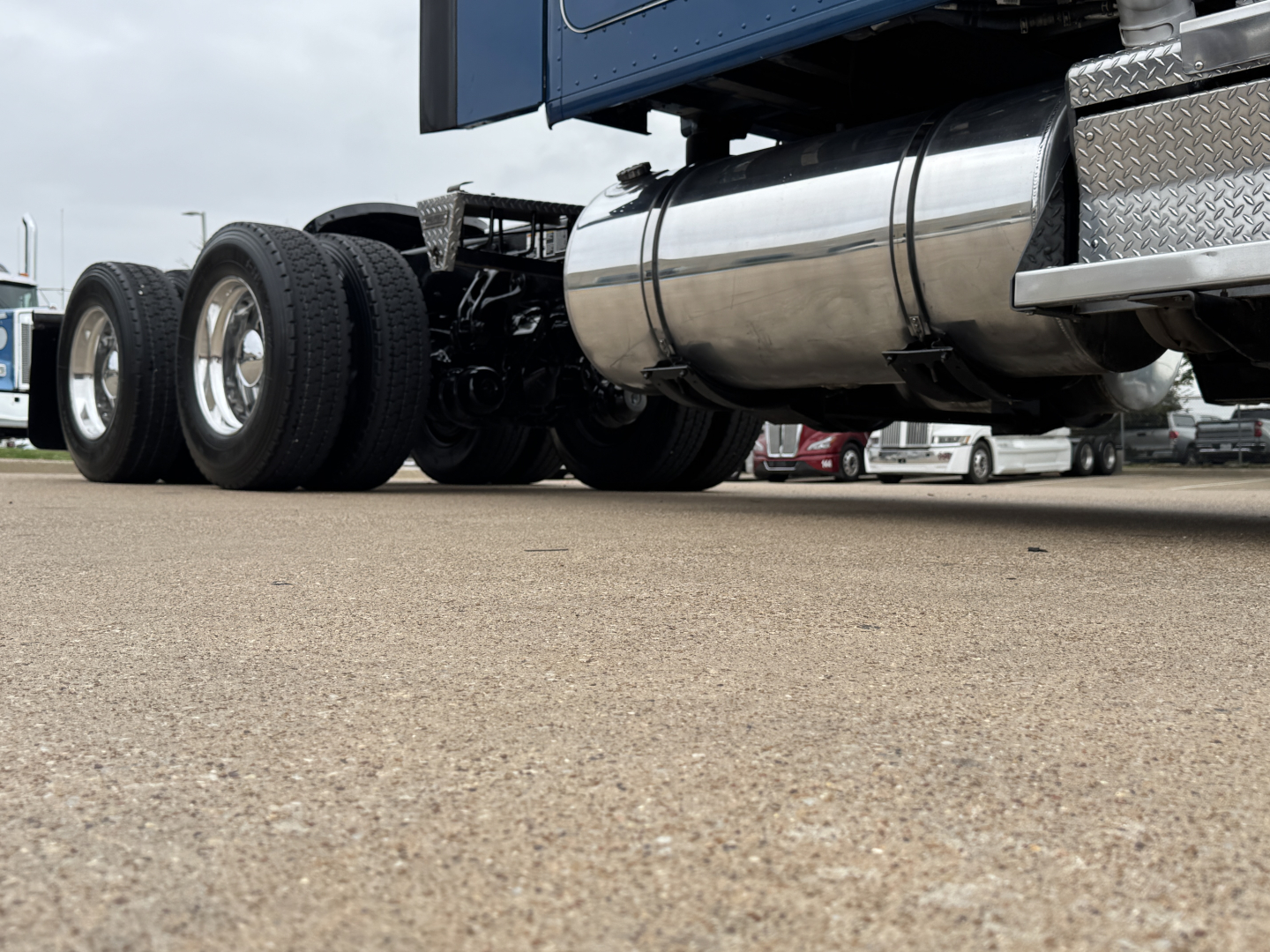 Kenworth T880 tractor rear view showing polished diesel fuel tank, dual rear axles, and wheels.