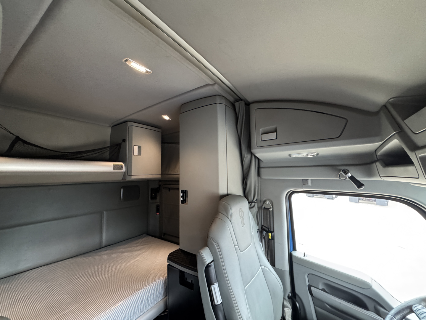 Kenworth T880 sleeper cab interior showing upper bunk, storage cabinet, and driver seat in a right-hand view.