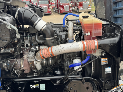 Kenworth T880 engine bay with intercooler piping, coolant reservoir, hoses, and turbo visible.