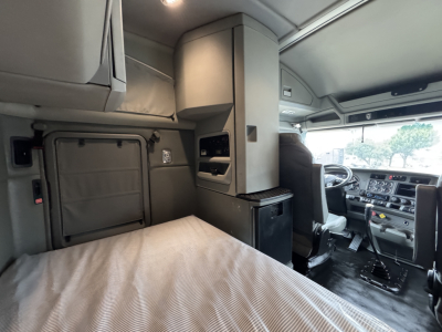 Kenworth T880 interior cab with sleeper berth, dashboard, and driver's seat visible; overhead compartments and storage cabinets in view.