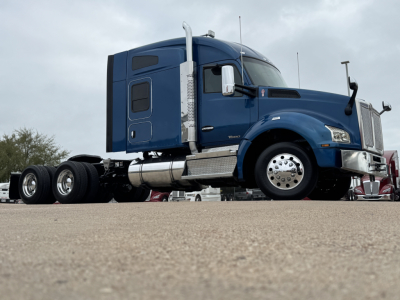 Kenworth T880 sleeper cab tractor in blue, side view showing fuel tanks, chrome wheel covers, and large front grille.