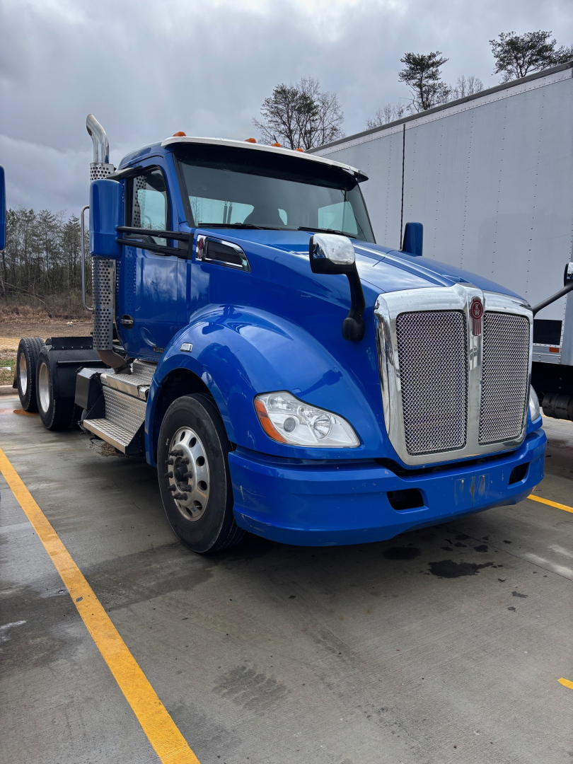 Kenworth T680 truck in blue, front three-quarter view showing chrome grille, large headlights, side mirrors, and steps.