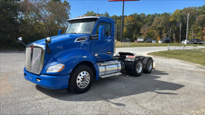 Kenworth T680 2021 blue conventional daycab truck side view showing chrome fuel tanks and dual rear axles.