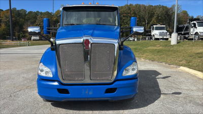 Kenworth T680 front view with blue cab, chrome grille, and large bumper; two rectangular headlights; side mirrors; blue exterior.