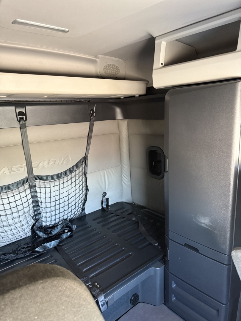 Freightliner Cascadia 126 cab interior showing sleeper storage area with overhead shelf and side cabinet.