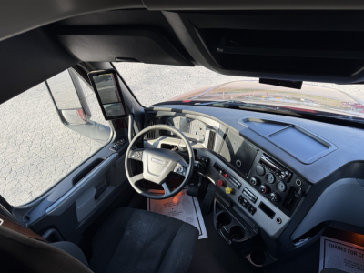 Freightliner Cascadia126 truck cab interior showing steering wheel, dashboard, and driver’s seat from a wide-angle view.