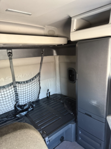 Freightliner Cascadia 126 cab interior showing sleeper storage area with overhead shelf and side cabinet.