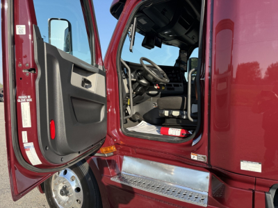 Freightliner Cascadia 126 truck cabin doorway view showing driver seat and dashboard with steps and door panel.