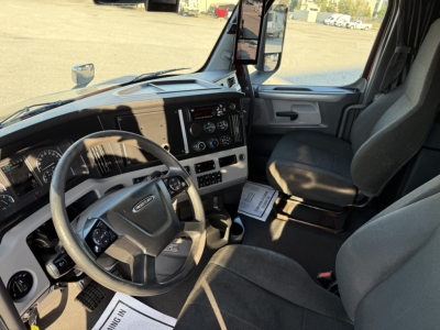 Freightliner Cascadia126 truck cab interior showing steering wheel, dashboard gauges, and driver seat with center console.