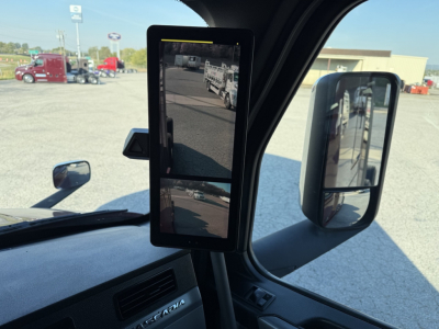 Cab interior showing a flip-out mirror display and side mirror in Freightliner Cascadia. Dashboard vents visible.