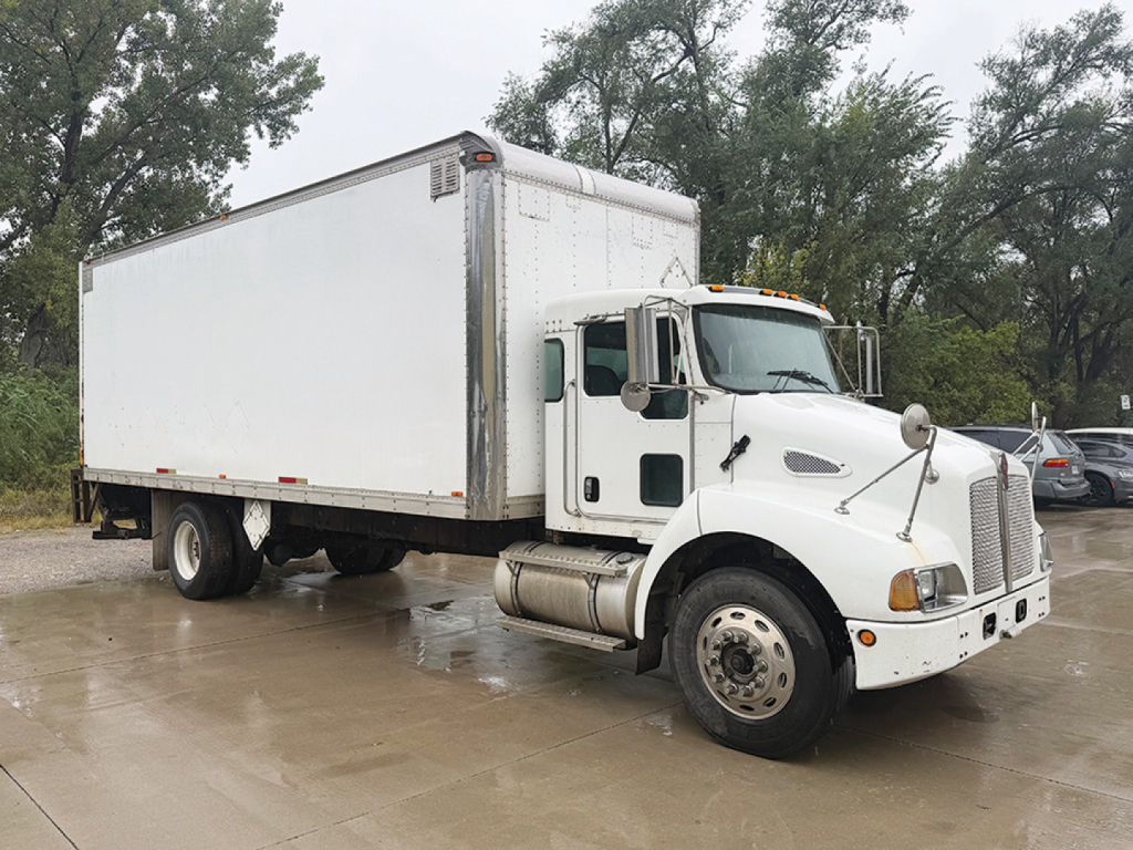 Kenworth T-300 conventional daycab truck with a large box cargo body, front view angled, white cab and box, stock number 559829 visible.