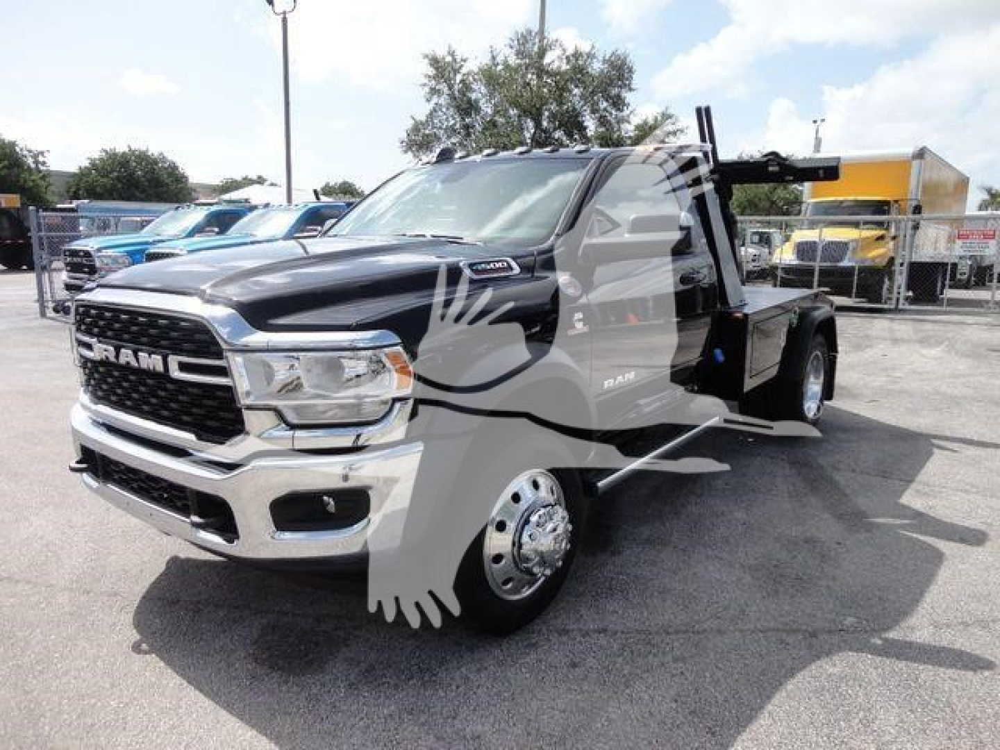 Ram 4500 truck in a dealership lot with a heavy duty winch carrier on a flatbed. The front grille shows RAM and the headlights are clear. Decals and a side step are visible along the cab.