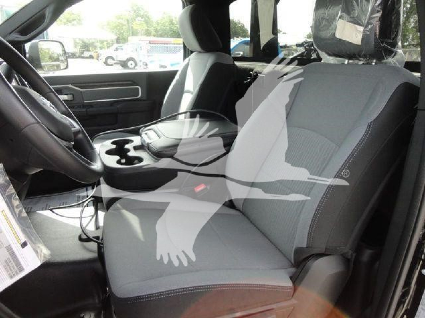 Ram truck interior front seats with center console and cup holders, dashboard and steering wheel visible.
