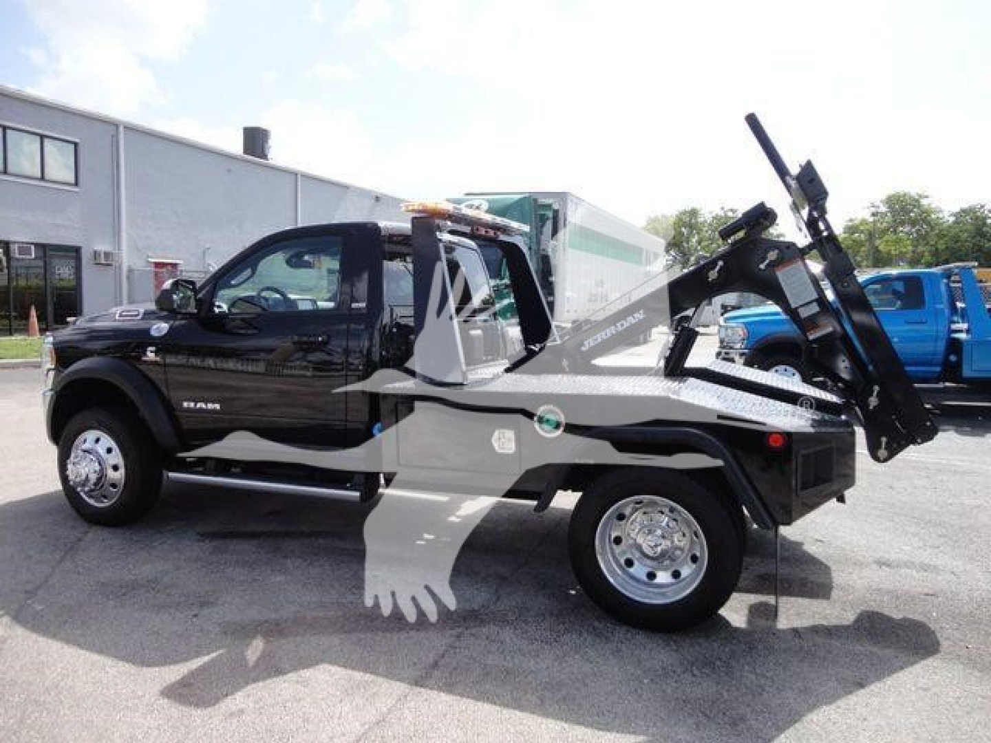 Tow truck side view showing Ram 4500 SLT with winch equipment and hydraulic tilt bed, black exterior, stock number J33421FM visible, new truck.