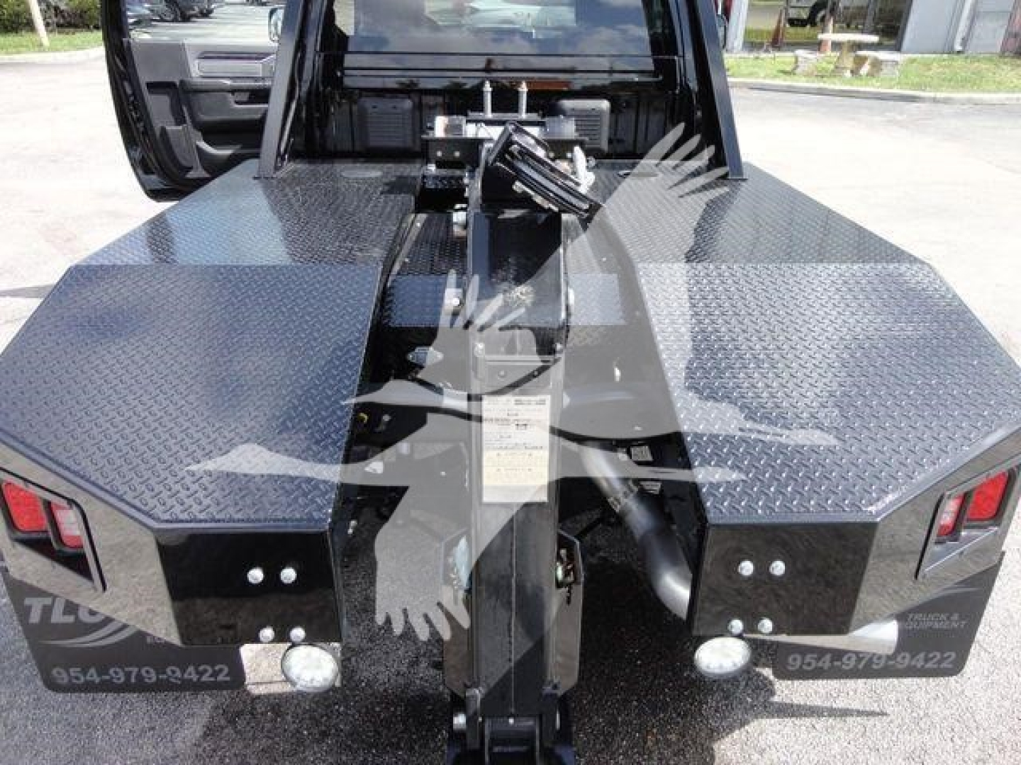 Truck bed with winch mount and diamond plate surface, Ram 4500 SLT. Hydraulic winch components centered; rear of truck visible with taillights and fuel doors.