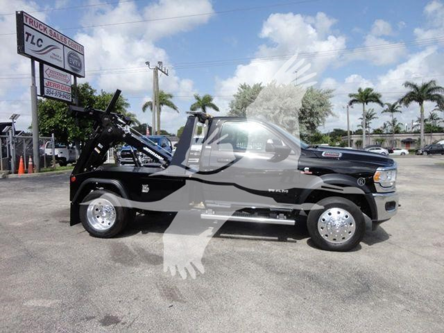 Ram 4500 tow truck side view with winch equipment on front, black exterior, silver wheels, palm trees in background.
