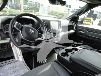 Ram pickup truck interior showing steering wheel with Ram badge, center touchscreen display, gear selector, and cupholders in the console.