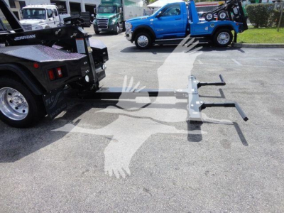 Ram 4500 winch truck with tow hitch accessories and lifting arms attached to tow truck chassis, on pavement.