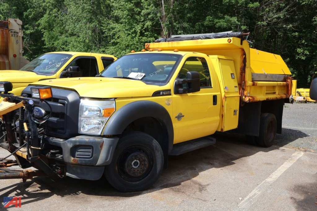 Ford F-450 Super Duty dump/sander/plow truck in serviceable condition with yellow body and utility bed.