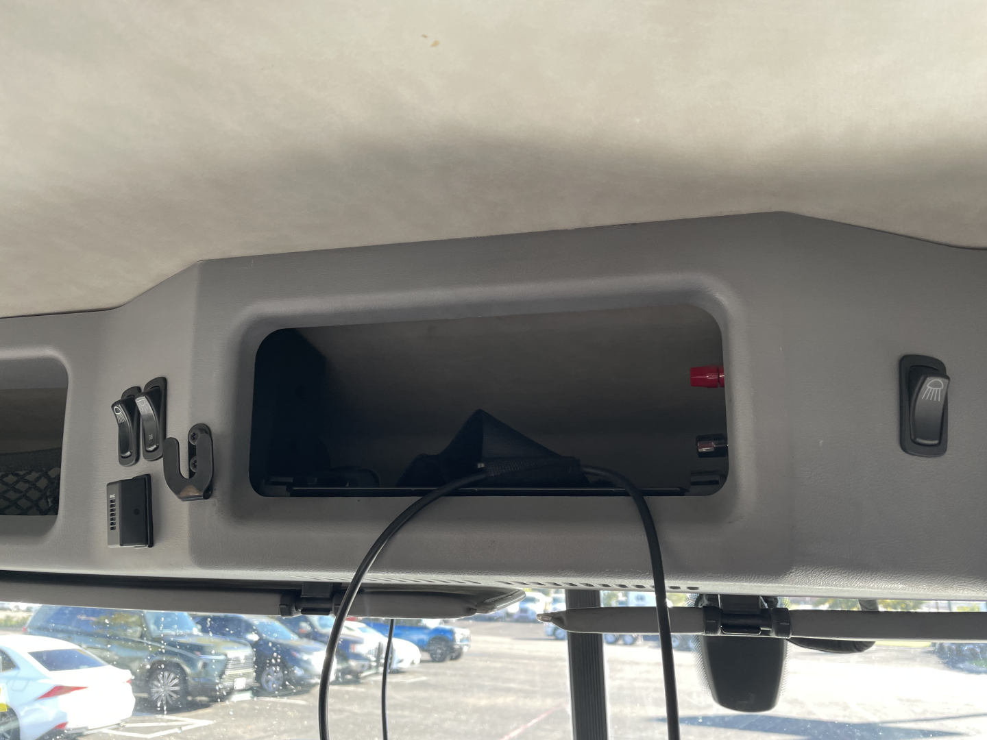 View of a truck cab interior dash area showing a hollow storage compartment with a cord/strap and switches nearby.