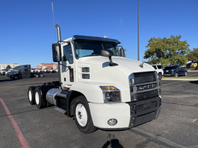 Truck front-left view of a white 2020 Mack AN64T with large grille, dual rear axles, fuel tanks on side, and mirrors. Visible text includes Mack grille and headlights.