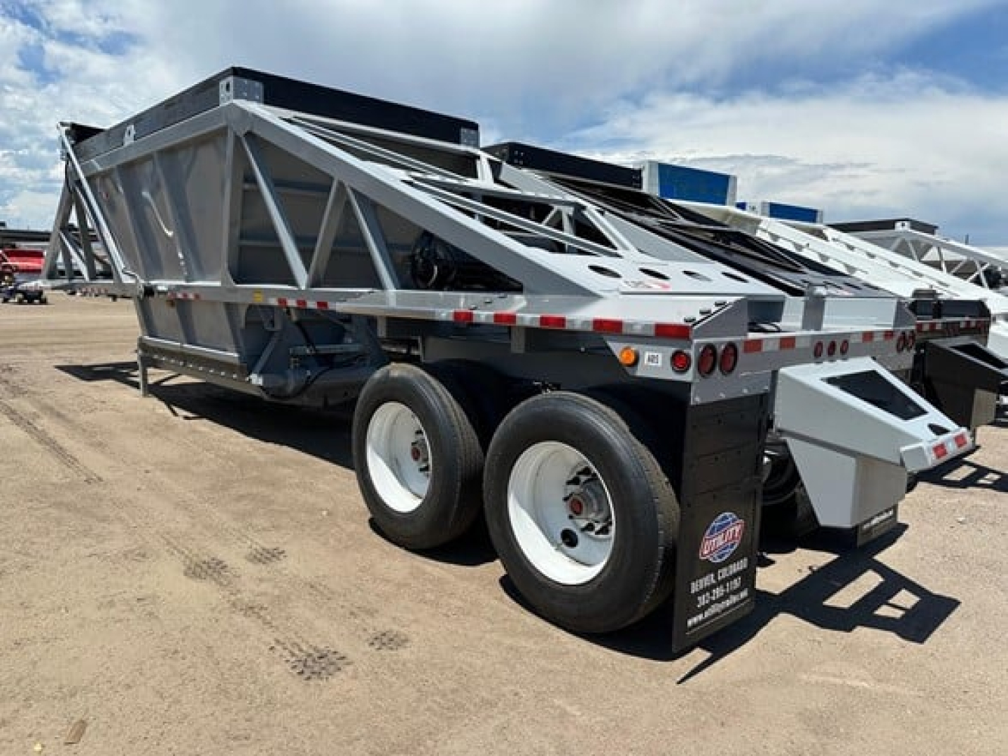 Trailer showing CPS lightweight air ride bottom dump with electric tarp and dual rear axles on a heavy-duty trailer.