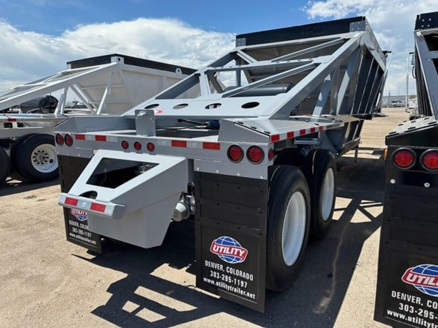 Dump trailer with electric tarp system, lightweight air ride bottom dump, dual rear axles, aluminum frame, rear toolbox, Utility brand mudflaps, stock and VIN text not legible.