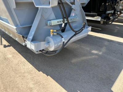 Trailer hitch area showing hydraulic actuator and hose fittings for air ride bottom dump trailer.