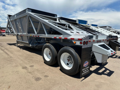 Trailer with dual-axle bottom dump frame and hydraulic components visible; metal lattice sides, rear hinge, and wheel wells; white rims and black tires; reflective tape along the edge.