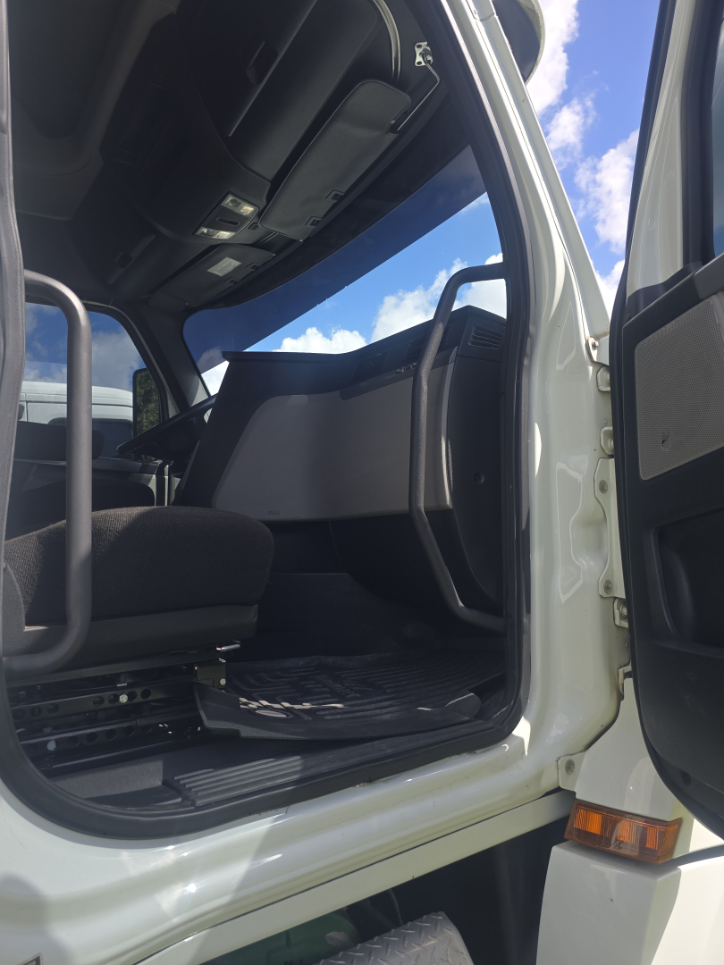 Truck cab interior of a Freightliner Cascadia showing entry step and open driver door with dashboard and seat visible.