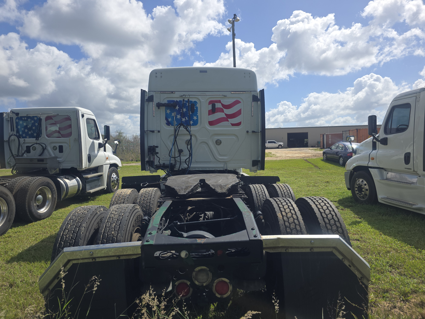 Freightliner Cascadia tractor cab rear view showing fifth wheel and dual rear axles with American flag graphics on the sleeper door.