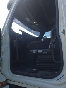 Truck cabin interior door opening showing dashboard controls and seat in Freightliner Cascadia cab