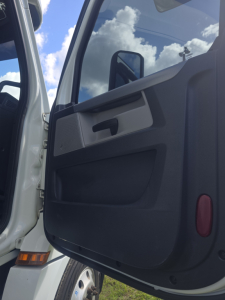 Truck door interior panel of a 2020 Freightliner Cascadia conventional sleeper, open door view with handle and window mirror visible.