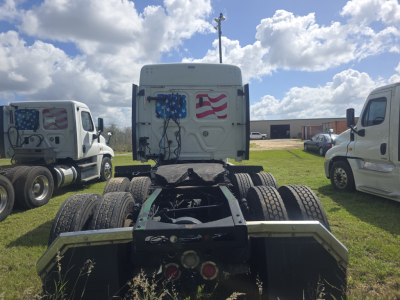 Freightliner Cascadia tractor cab rear view showing fifth wheel and dual rear axles with American flag graphics on the sleeper door.