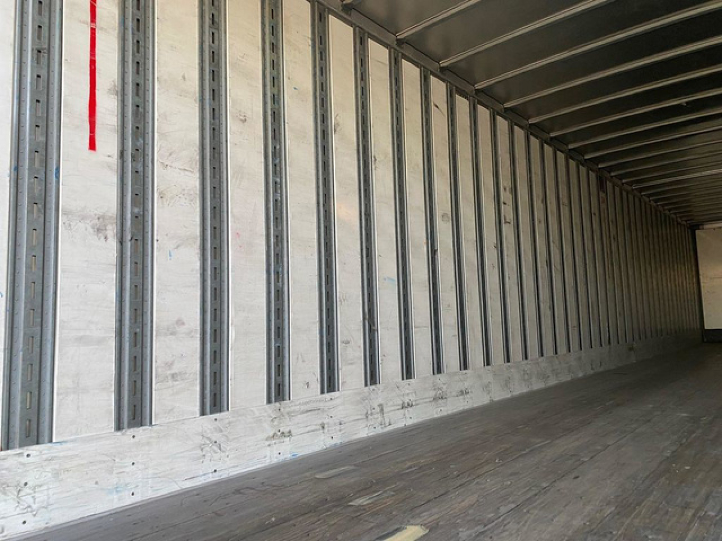 Interior of a 2013 Stoughton van trailer showing metal interior walls with vertical railings and a wooden floor.
