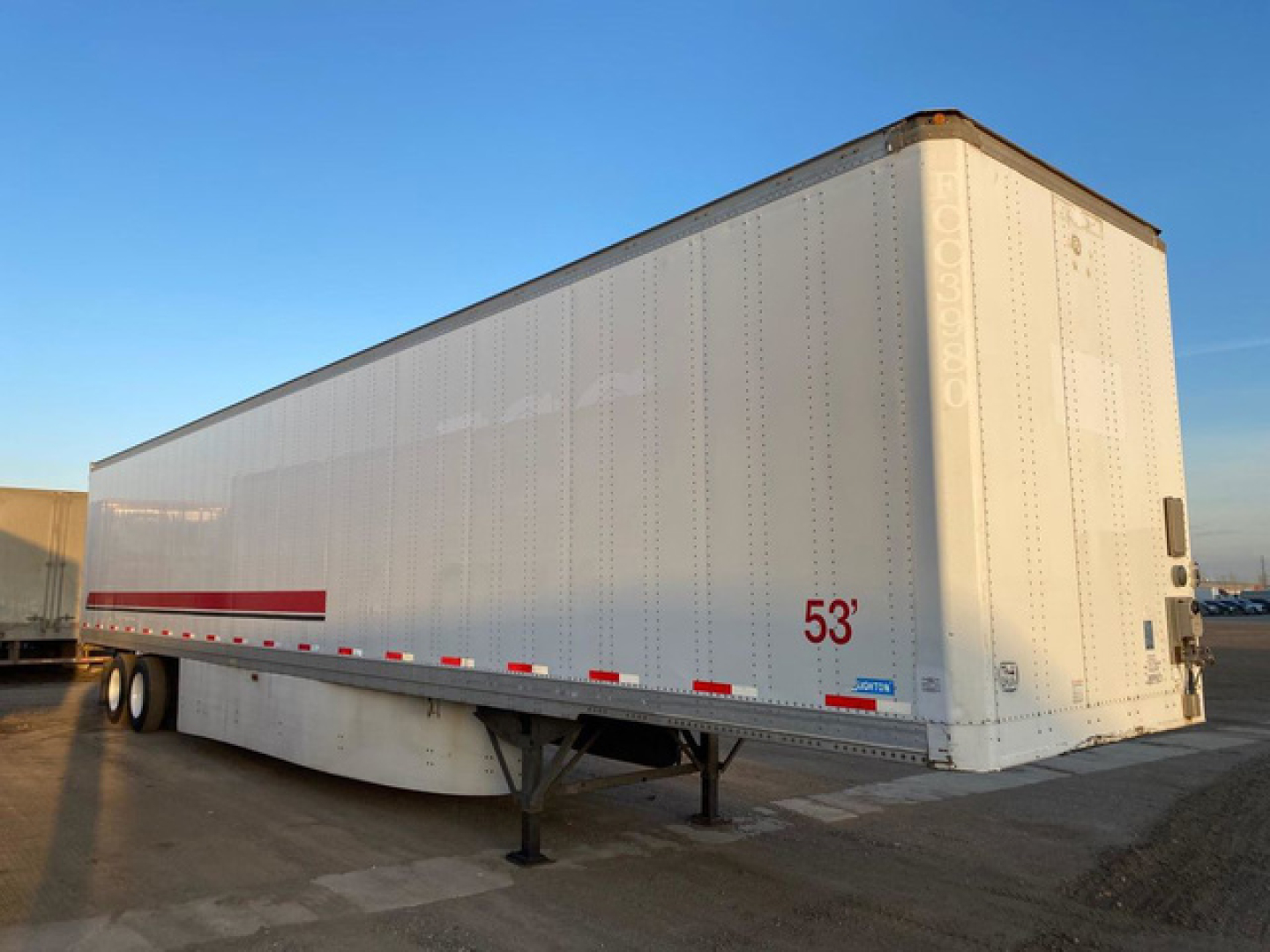 A 2013 Stoughton van trailer showing a white exterior with red reflective stripes, 53' length marking, riveted panels, tandem axle and front landing gear.