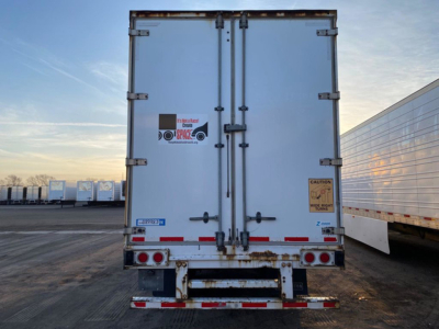 Rear view of a 2013 Stoughton van trailer with double doors, visible hinges, latches, and warning stickers; rust on frame and bumper with reflective tape.