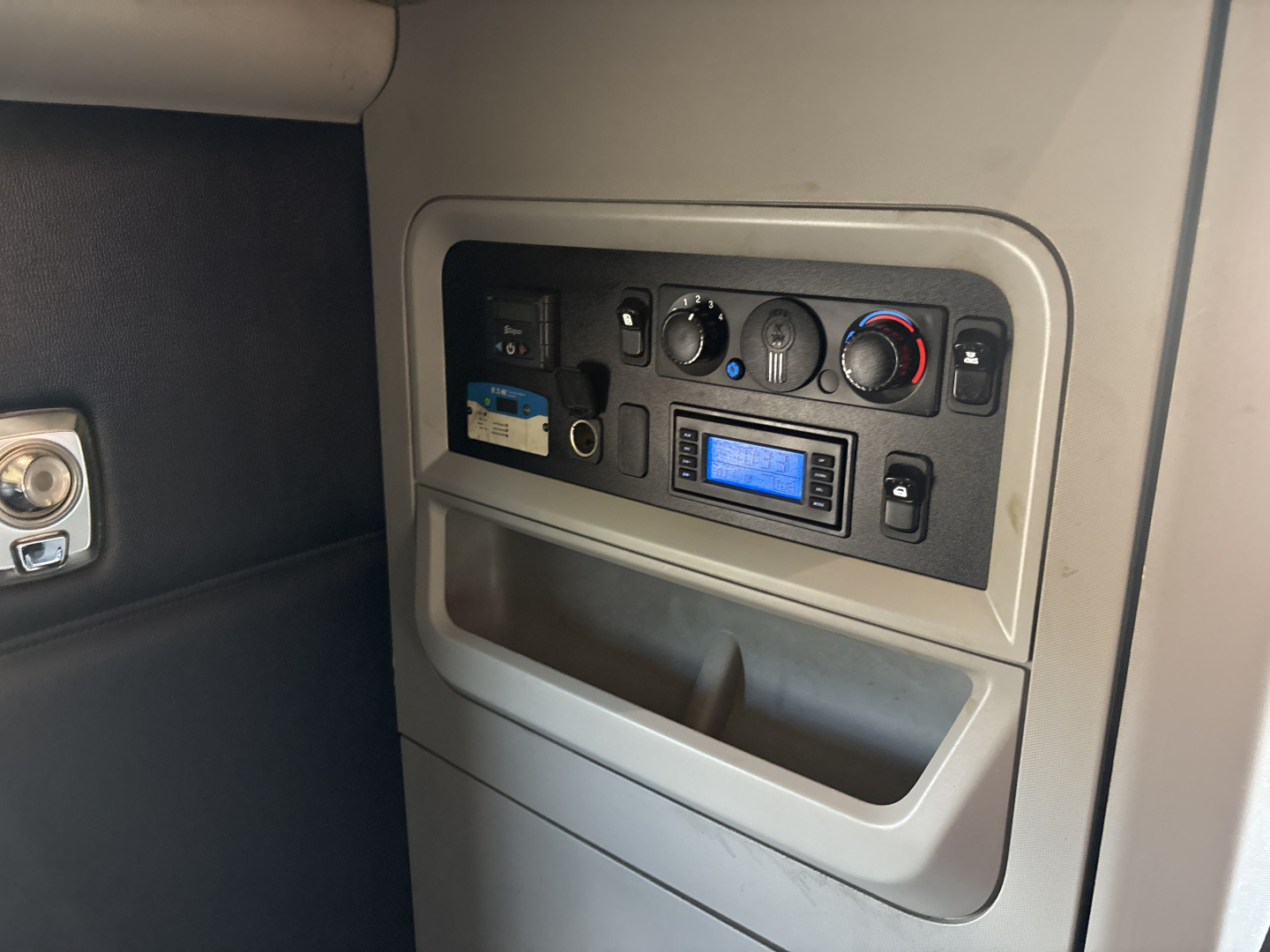 Kenworth T680 dash panel showing climate controls, radio, and storage pocket in cabin interior.