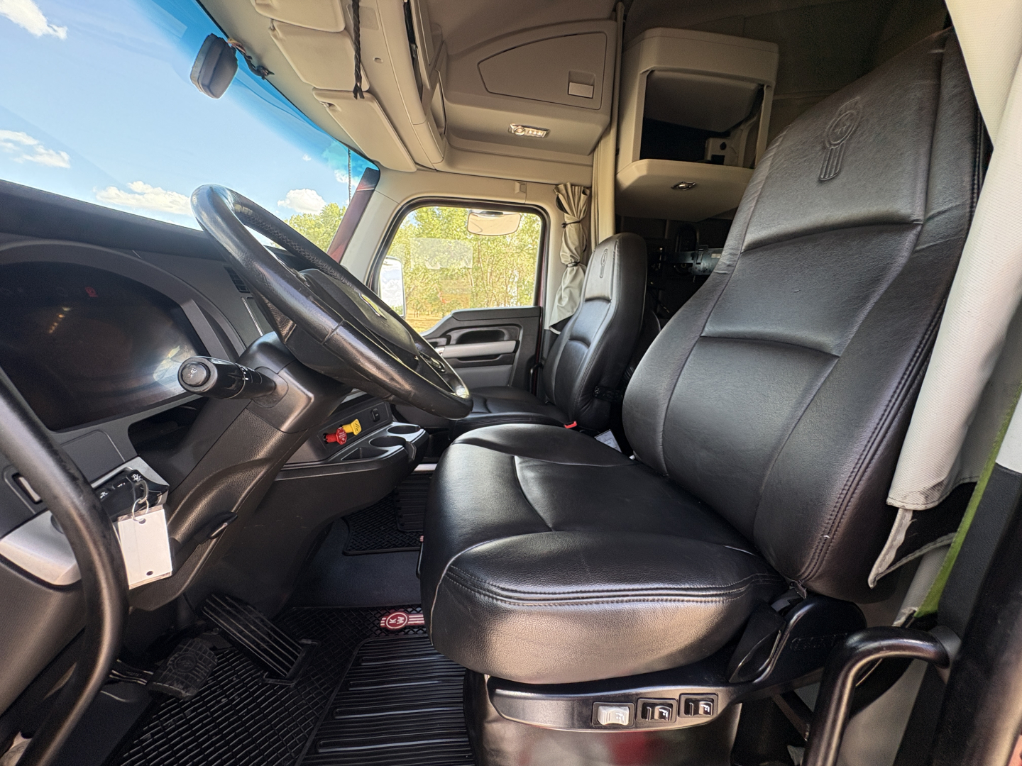 Truck cabin interior with driver's seat and passenger seat visible; steering wheel and dashboard show controls.