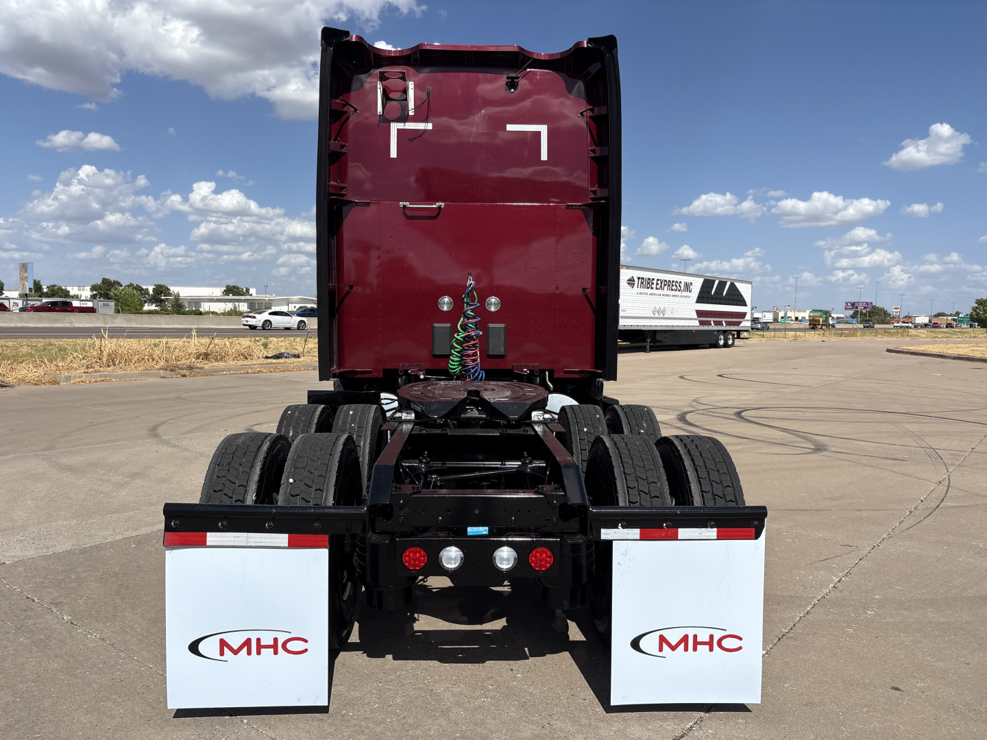Kenworth T680 rear view showing dual rear axles and mud flaps with MHC logo.