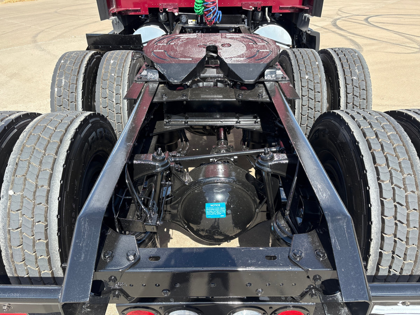 Kenworth T680 rear undercarriage showing dual rear axles, chassis, differential with blue tag, and mounting hardware.
